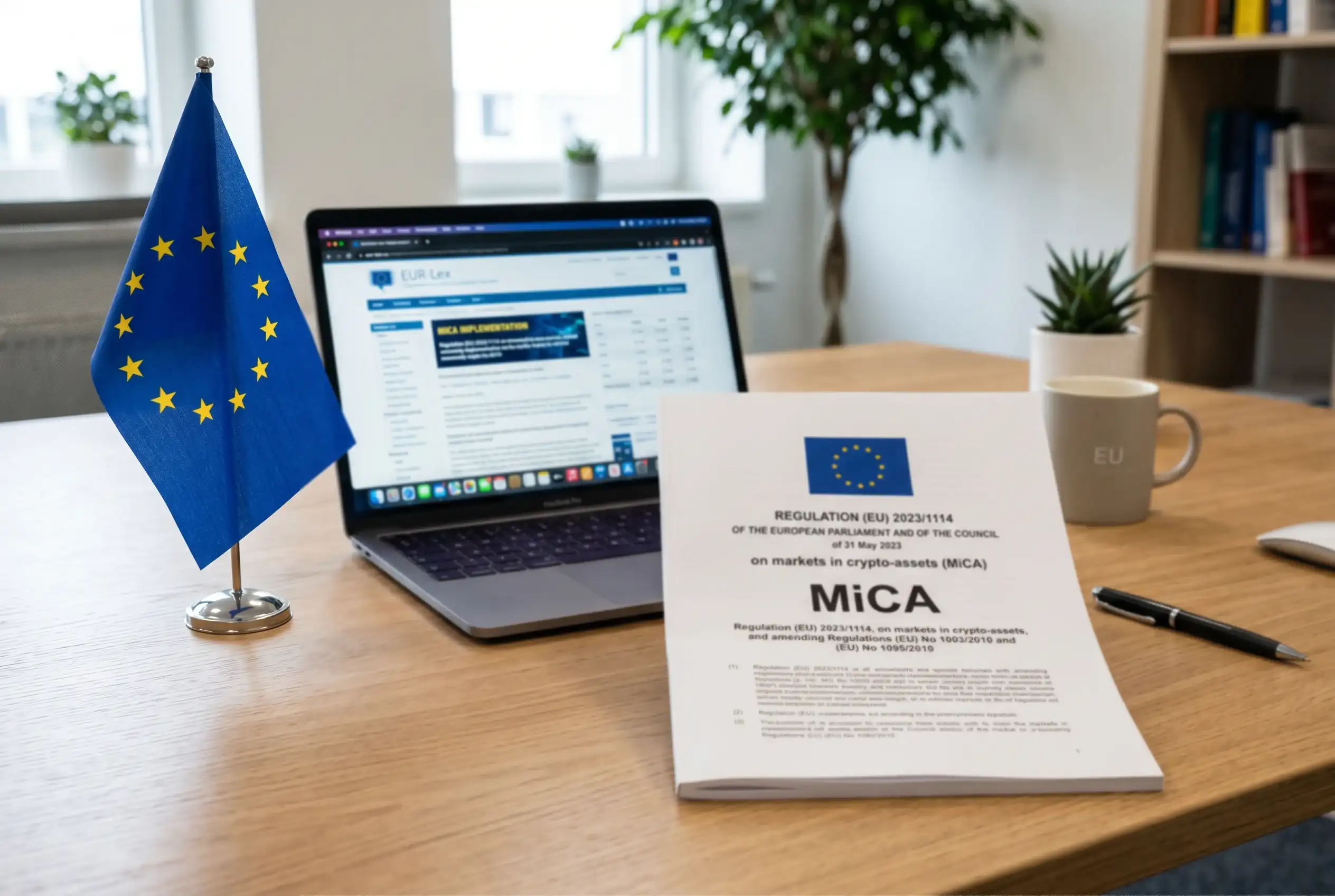 Documento del reglamento europeo MiCA sobre una mesa de oficina junto a una bandera de la Unión Europea y un portátil